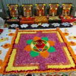 A colorful rangoli made of flower petals on a white floor. and gods photo